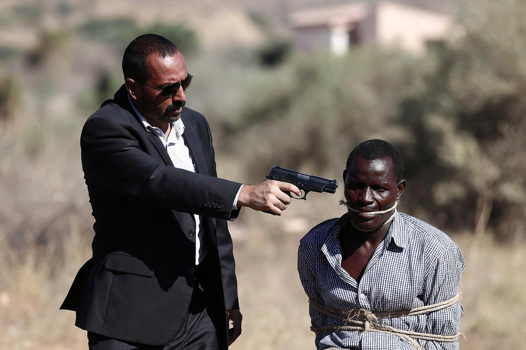 Homme en costume pointant un pistolet sur un otage ligoté et bâillonné en zone rurale, illustration de la criminalité organisée et des enlèvements à Madagascar